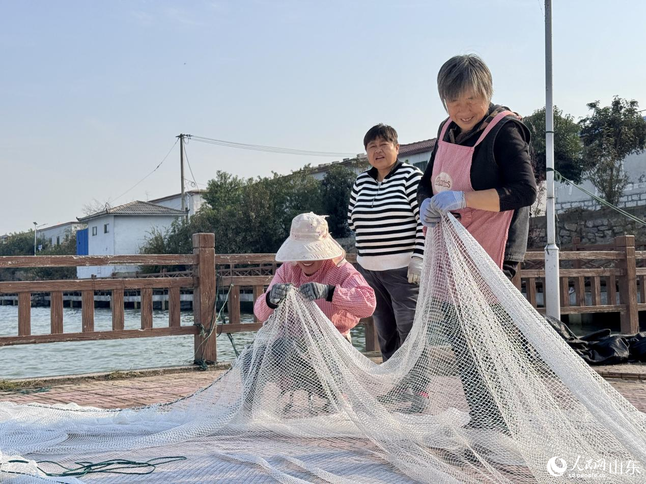 村民脸上洋溢着笑容,正在织捕鱼网箱。人民网 郑昕桥摄