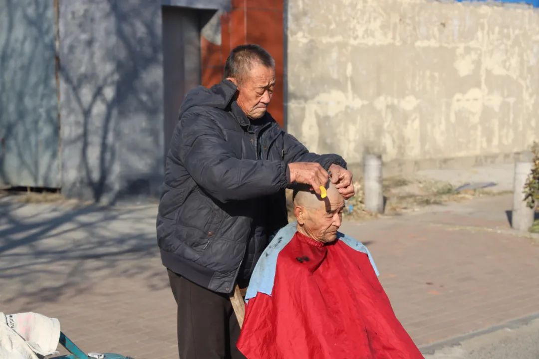 乡村集市上,几个剃头的摊位,六七十岁的老人用着老手艺,奉行着老传统