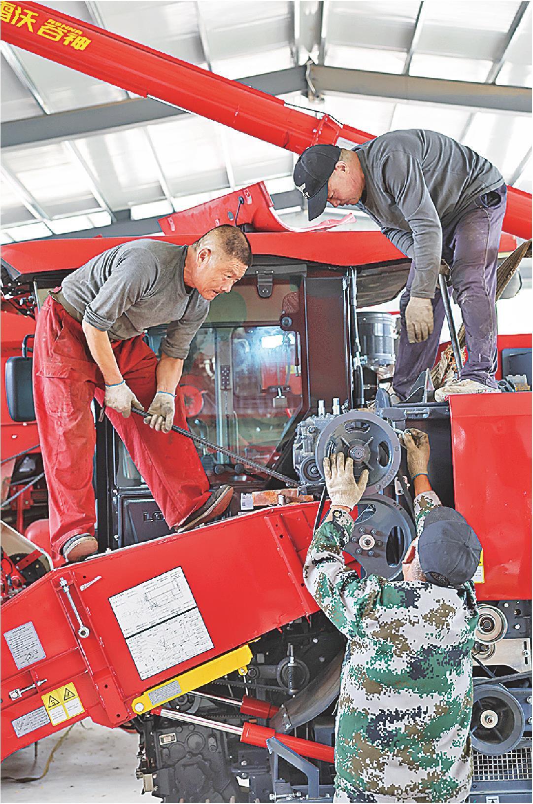 10月16日，济南市莱芜区口镇街道安太农机合作社的工作人员正在为新进的履带式收割机更换玉米割台。(卢鹏摄)